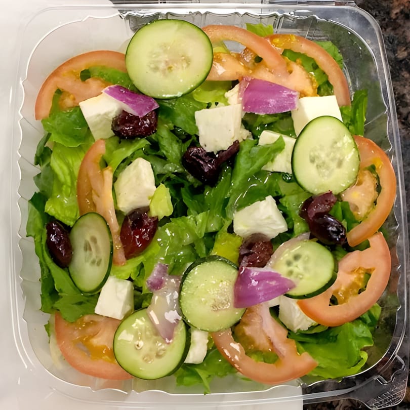 Fresh La Pizzeria salad with lettuce, tomatoes, cucumbers, feta cheese, red onions, and olives.