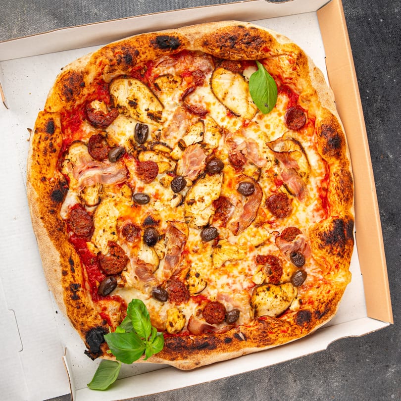 La Pizzeria's pizza with chicken, pepperoni, olives, and basil in a delivery box.